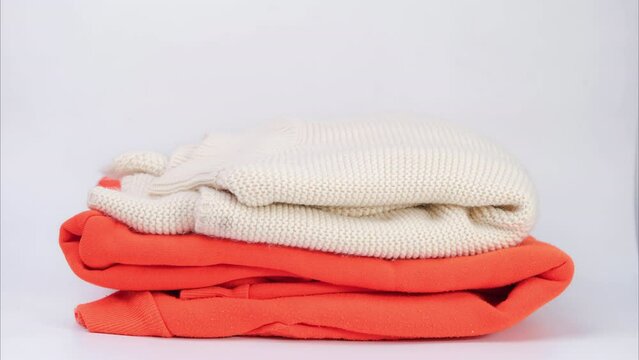 Stop motion of piles of colorful clothes on white background. Clothes for donation or shopping. Household laundry.