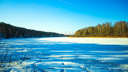 Winter landscape on a frozen lake. The forest is on the horizon. The river is under the ice