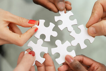 Multi-ethnic hands - assembling puzzle - symbol of teamwork and solutions, collaboration and...