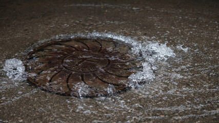 Water pipe burst, water Water flows out of the manhole onto the asphalt. The accident in the sewer....
