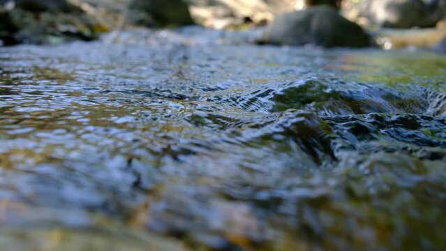 Closeup.Stream of water flows with large gray rocks in the background.