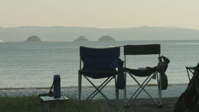 Camping Scene with Ocean View at Dusk, Two Chairs Overlooking Secluded Bay