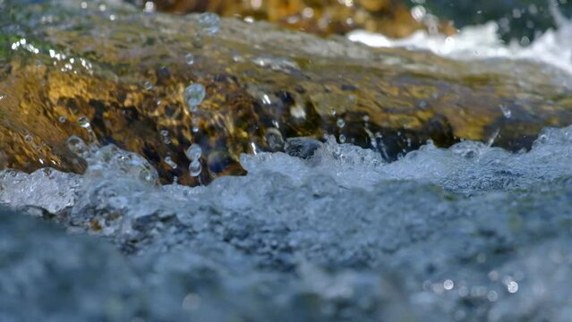 A fast-flowing stream of water hit the rocks and created many air bubbles.