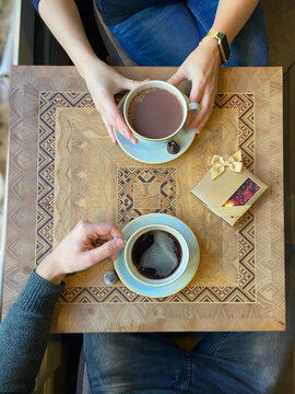 Scene Table From Above: Romantic Coffee Date &ndash; Couple Enjoying Cozy Caf&eacute; Moment with Hot Beverages and Gift Box on Wooden Table