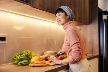 A middle aged japanese woman is preparing healthy lunch in kitchen.