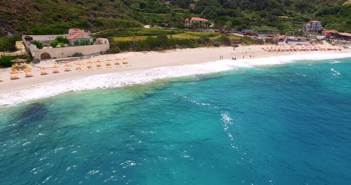 Drone panning in front of the Petanoi Beach shoreline while showing the white, sandy shoreline facing the Mediterranean Sea in Greece.