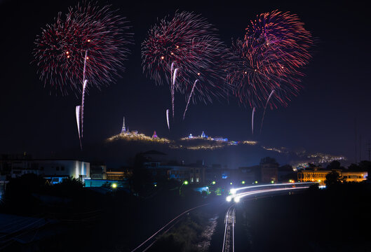 Firework over the mountain in the festival (Phra Nakhon Khiri) and motion blor headlight of the train, city lights at night scene Phetchaburi province. Thailand.