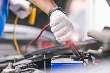 a mechanic using jumper cables to manually power a car's battery