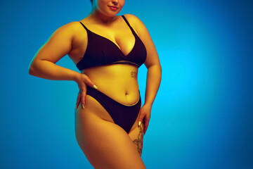 Woman, model plus size in dark lingerie, showcasing natural body curves in yellow neon light...
