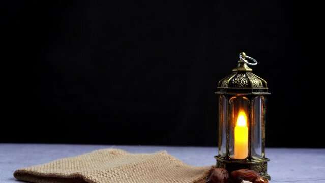 take and serving a wooden bowl of date palm fruits with antique ornament lantern on isolated black background