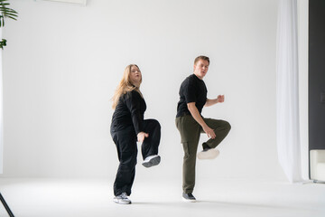 Energetic Pair Of Man and Woman Showcasing Modern Dance Moves in a Bright Studio Setting