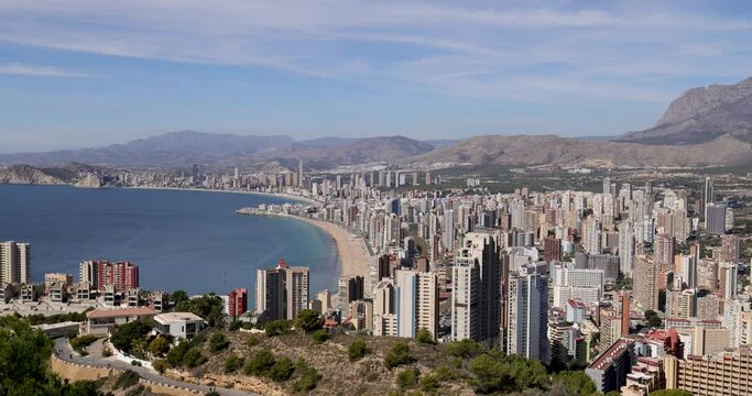 Footage of the town of Benidorm in Spain in the summer time taken from the northern hill in the summer time showing many high rise apartments and building along side the Levante Beach