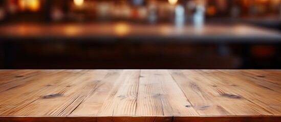 An unadorned wooden table sits on a hardwood floor in a restaurant, the blurry background highlighting the natural beauty of the wood grain - obrazy, fototapety, plakaty