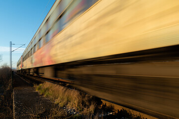 Train passing with motion blur, railroad travel passenger train during sunny day