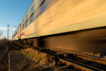 Fototapeta premium Train passing with motion blur, railroad travel passenger train during sunny day