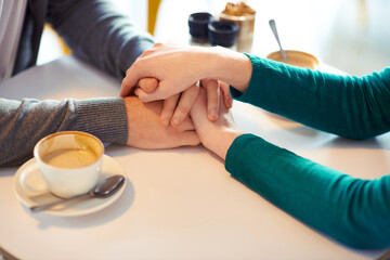 Holding hands, couple and coffee in cafe with love, romance and affection on anniversary date. Respect, together with care and bonding, loyalty and support in relationship with cappuccino for people