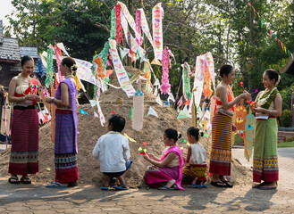 Group of Thai women and children in traditional Thai costume decorating sand mountain with colorful flag celebrating Songkran festival in Chiangmai Thailand