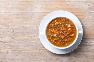 Lentil soup with vegetables in bowl on wooden table. Top view. Copy space
