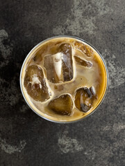 A glass of iced coffee on a dark background.  Top view.