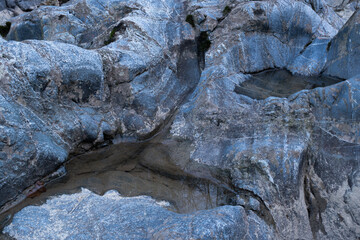 Small puddle in blue rock close up, dent in stone filled with water during blue hour