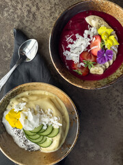 Colourful smoothie bowls beautifully decorated with fruits, nuts and edible flowers. Top view
