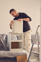 Man working and assembling furniture in a new apartment.