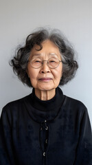 Une personne âgée de type asiatique portant des lunettes de vue au format portrait.
