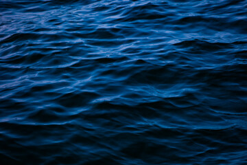 Blue ocean water with waves background. An abstract background of seawater flow under light exposure.