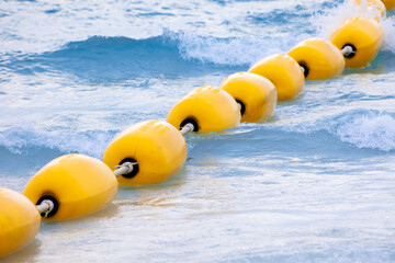 Yellow sea buoy. Ocean with floating buoys and rope dividers on the beach. Clear blue water and sandy beach. Sea background. - obrazy, fototapety, plakaty