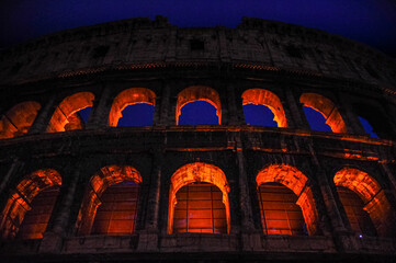 the colosseum in rome at night from below detail of the illuminated arches with hypersaturated colors in the background the blue sky of twilight