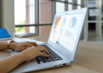Closeup businesswoman hand typing on laptop computer keyboard. Working atmosphere in modern office with large glass window. Side view