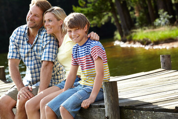 Nature, dock and parents with son by river for summer vacation, holiday and bonding in forest. Lake, smile and happy family with love for weekend adventure, travel and tourism together in Europe