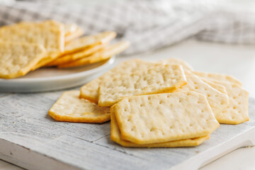 Golden Baked Crackers on cutting board on a White kitchen table.
