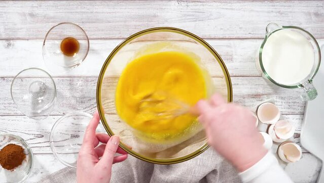Step by step. Mixing ingredients in a large glass mixing bowl to prepare French toast.