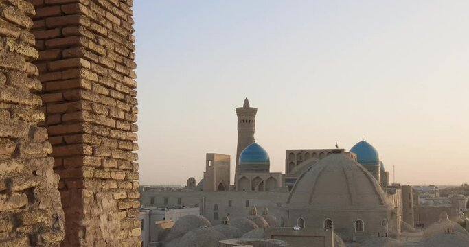 Po-i-Kalyan or Poi Kalan complex at sunset. Old Bukhara from the roof at sunset. Birds flying over Po-i-Kalan complex. Handheld shoot