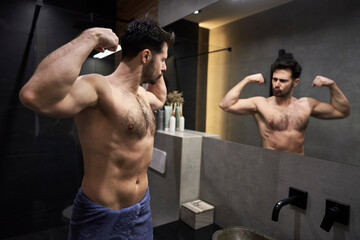 Fototapeta na wymiar Caucasian man flexing muscles in the mirror