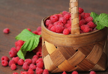 Fresh red raspberries in the basket on wooden background