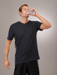 Healthy, studio or man drinking water for fitness, hydration or workout break isolated on grey...