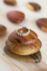 Textured silver ring on a wooden holder and soft wooden background. Handcraft precious item. Jewelry accessories.