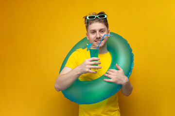 portrait of a young guy on vacation in the summer with a blue cocktail, a man with an inflatable ring - obrazy, fototapety, plakaty