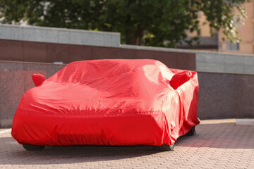 luxurious red roadster in cover protects against rain of dust and dirt