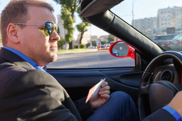 young businessman behind wheel driving luxury roadster, close-up