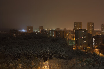 snow in spring in Moscow, city landscape from window of multi-storey building, evening
