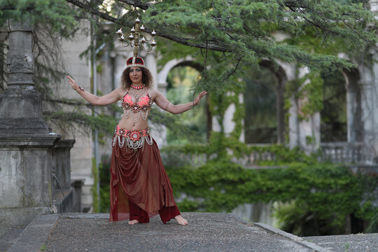 dancer dancing belly dance with chandelier on head on background of building of Ordzhonikidze sanatorium