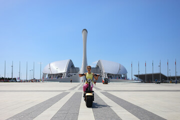 girl on scooter on background of bowl of Olympic flame Firebird