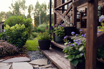 front porch decorated with flower pots. Rustic wooden cottage stairs with rattan pots and candles....