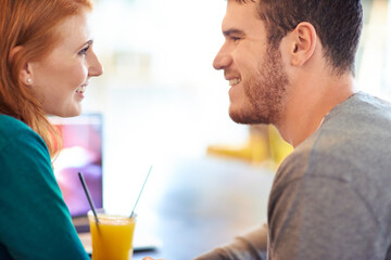 Happy couple, smile and eye contact in cafe with love, romance and affection on anniversary date. Romantic, man and woman in restaurant bonding with juice, beverage and laughter in relationship