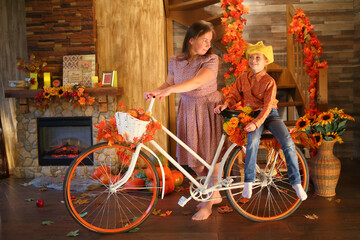 Mother is carrying her daughter on bicycle in front of fireplace and stairs in the room