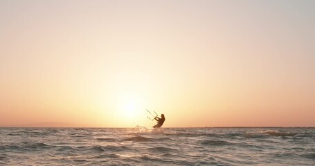 Silhouette of a kite surfer riding a kite surf at sunset. Kitesurfing. Watersport summer adrenaline activity