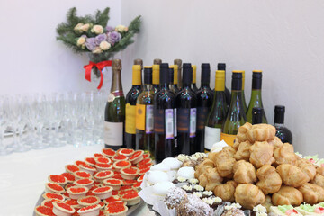 Wine, wineglasses, cakes and tartlets with red caviar on buffet table